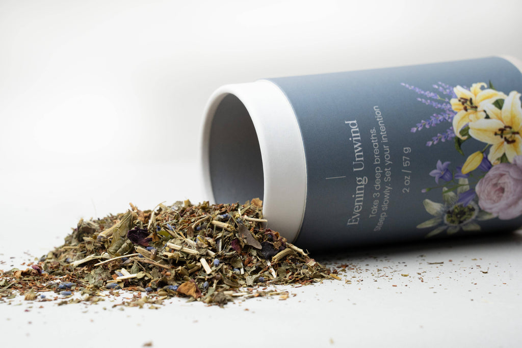 Zabelia Evening Unwind Calming Rooibos Herbal Tea in a glass mug with herbs and dried rooibos leaves inside.