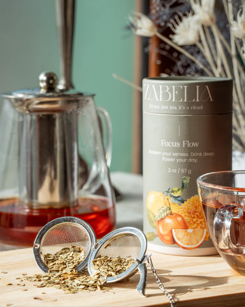 Focus Flow energizing Yerba Mate tea blend by Zabelia Wellness displayed on a desk with a cup and tea leaves.
