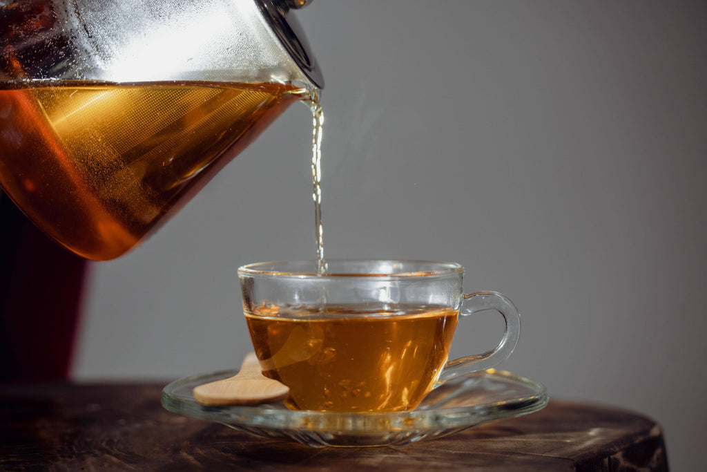 Steeped Zabelia Wellness Focus Flow energizing yerba mate tea in a glass cup with tea leaves and vibrant background.